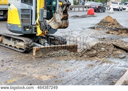 A Small Mobile Road Excavator On A Crawler Chassis Cleans The Roadway From Dirt And Repairs The Sewe
