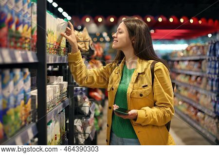Woman In Yellow Jacket Chosing A Groceries In The Supermarket