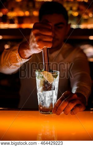 Hand Of Male Bartender Press Ingredients For Mojito Using Muddler At Bar. Close-up