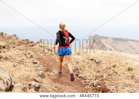 Young Woman Trail Running In Mountains