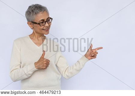 Happy Senior Woman Showing Thumb Up And Pointing Aside. Portrait Of Mature Caucasian Woman Wearing E