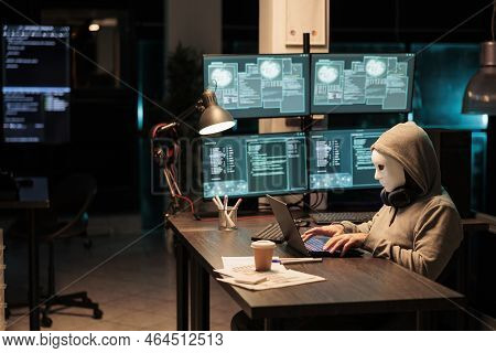 Scammer With Mask And Hood Hacking Security Server, Installing Virus To Create Computer Malware And 