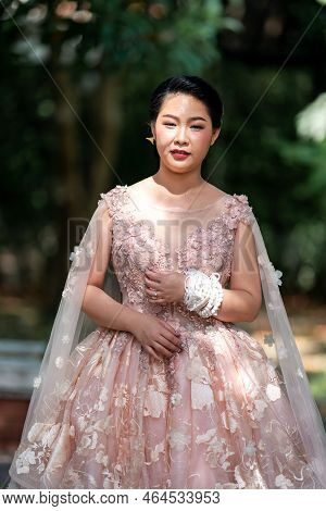 Asian Girl In An Old Rose Pink Color Knee Length Fluffy Dress With High Heel Slingback Shoes And Cer
