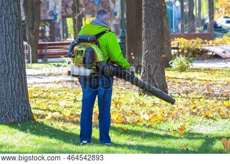 Leaf Blower Male Worker Removes Leaves Lawn Of Garden Autumn. Removing Fallen Leaves In Autumn. Park