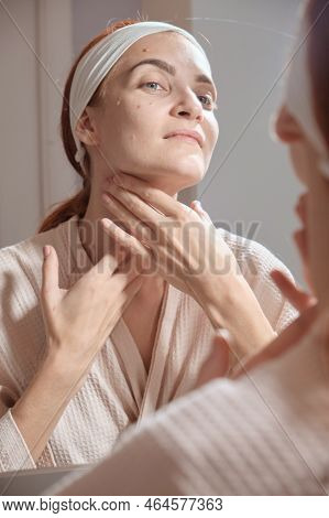 Beauty Day. Woman Doing Her Daily Skincare Routine In Bathroom And Mirror Gently Puts Cream On Her F