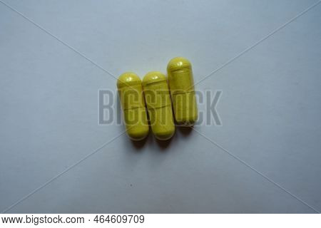 Group Of Three Greenish Yellow Capsules Of Quercetin Dietary Supplement From Above