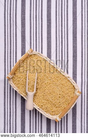 Traditional Dry Pearl Couscous In A Wicker Basket On A Textile Background. Top View.