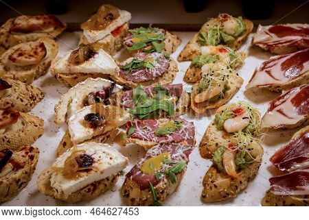 Many Tapas, Small Baguettes Pieces With Toppings On A Board.
