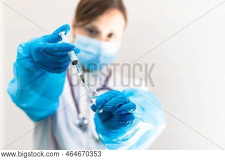 Young Woman Doctor In A Medical Mask And Gloves With A Syringe In Her Hand And A Stethoscope In A Ho