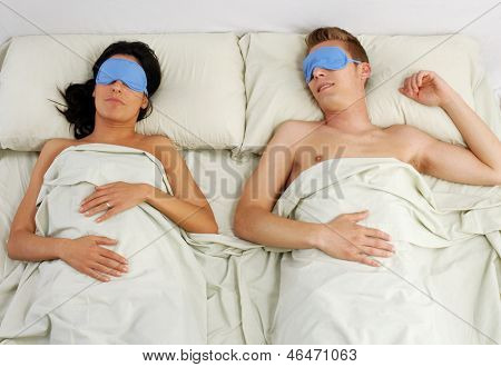 Couple en masque pour les yeux sommeil sur lit de couchage.