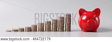 Close-up Of Stack Of Coins In Ascending Order And Red Piggy Bank On Table, Profitable Investment Of 