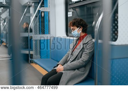 Masked Woman Sleeps Sitting On A Bench In A Subway Car.
