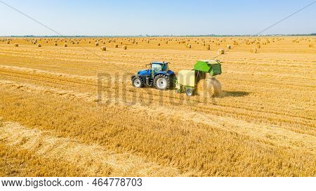 Above View On Tractor As Pulling Round Baler, Machine That Rolls Up The Straw And Spits Out A Packed