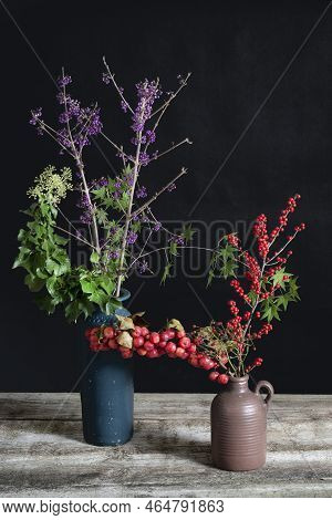 Callicarpa And Hedera Helix And Ilex In Blue And Brown Vases.