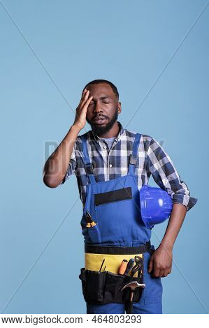 Stressed Builder In Uniform And Tired Hard Hat Rubbing His Head Feeling Fatigue And Headache. Frustr