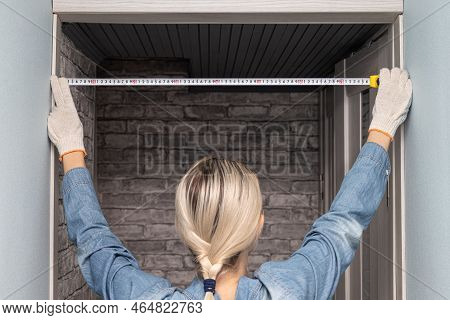 Woman Measuring A Doorway With A Tape Measure. Woman Using A Tape Measure. Woman Doing House Renovat