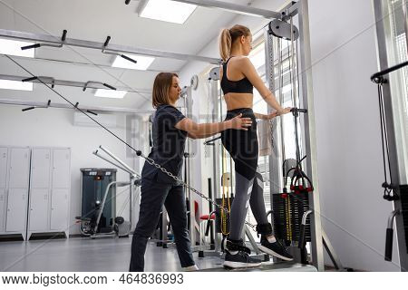 Rehabilitation Specialist Helping Woman To Do Exercises On Decompression Simulators At Gym