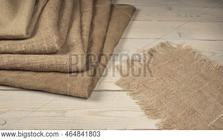A Stack Of Coarse Peasant Cloth - Burlap And A Tarpaulin On A Wooden Table. Rustic Style Image