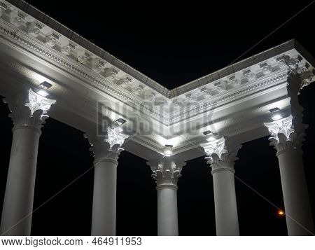 White Colonnade In The Dark. White Columns In The Light Of Spotlights. Street Decorative Architectur