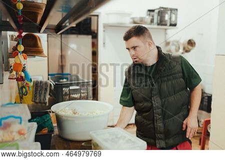 Man With Down Syndrome Working In Kitchen In Zoo, Prepairing Food For Animals.concept Of Integration