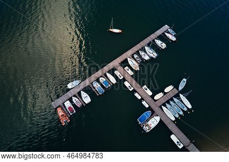 Aerial Top View Of Boats And Small Jachts Near Wooden Pier At The Lake. Summer Entertainment At Wate