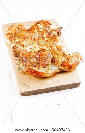 grilled Chicken Tabaka on wooden board, white backdrop