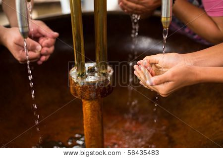 People filling up their hands with healthy mineral water from a wellspring in a spa (shallow DOF)