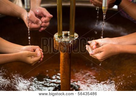 People filling up their hands with healthy mineral water from a wellspring in a spa (shallow DOF)