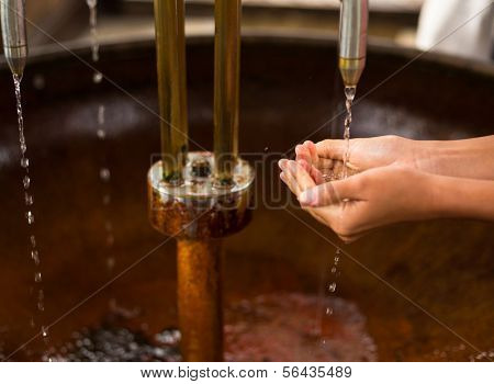 People filling up their hands with healthy mineral water from a wellspring in a spa (shallow DOF)