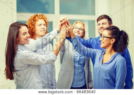 business, office, gesture and startup concept - smiling creative team doing high five gesture in office