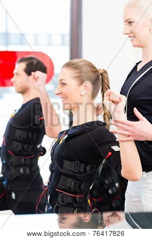 Female coach giving man and woman ems electro muscular stimulation exercise 