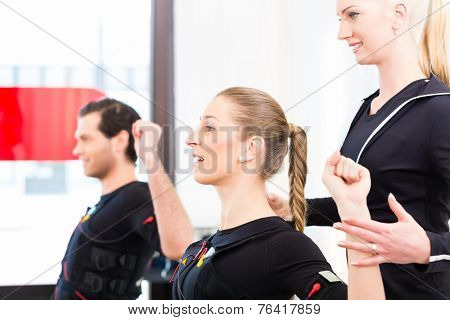 Female coach giving man and woman ems electro muscular stimulation exercise 