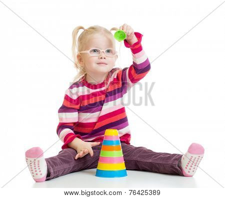 Funny kid in eyeglasses playing colorful pyramid toy isolated on white