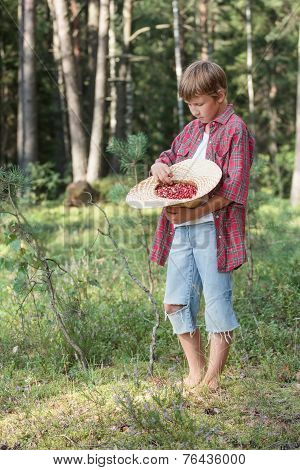 Teenage boy tasting fresh forest wildberries