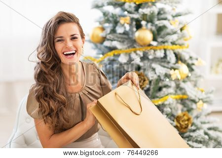 Happy Young Woman Opening Shopping Bag Near Christmas Tree