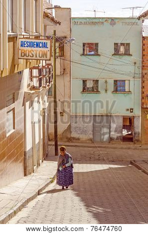 COPACABANA, BOLIVIA, MAY 6, 2014: Local woman in traditional costume and bowler hat walks down the street