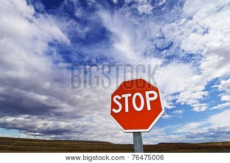 view of a stop signal with cloudy sky