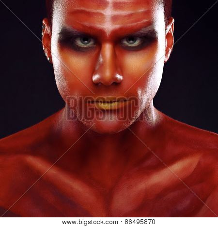 Portrait of a handsome young man in a red body painting