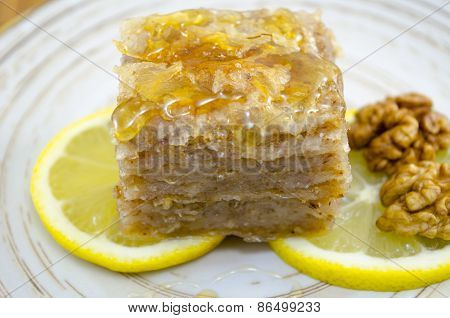 Juicy Baklava On A Plate Decorated With Lemon And Walnuts
