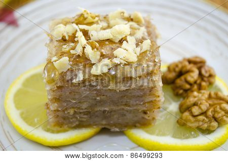 Juicy Baklava On A Plate Decorated With Lemon And Walnuts
