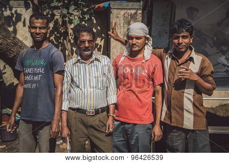 MUMBAI, INDIA - 09 JANUARY 2015: Three Indian men stand with construction manager. One man teases manager. Post-processed with grain, texture and colour effect.