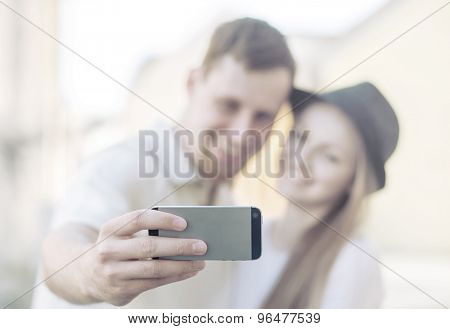 Touristic couple shooting on the modile phone at the city streets under sunlight.