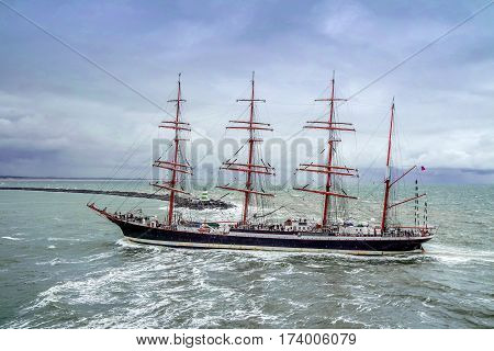 IJMUIDEN, NETHERLANDS - AUGUST 18 2015: Tall ship passing lighthouse in the rain