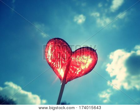 Red heart lollipop on blue sky background