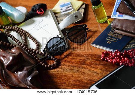 Travel background image of travel items ready to pack for adventure trip or vacation conceptual - on wooden desk with notebook, passport, sewing kit, travel sized shampoos, and other items