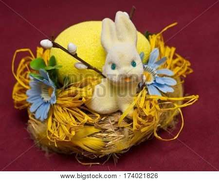 Cute white bunny sitting in a basket with flowers and colorful easter eggs