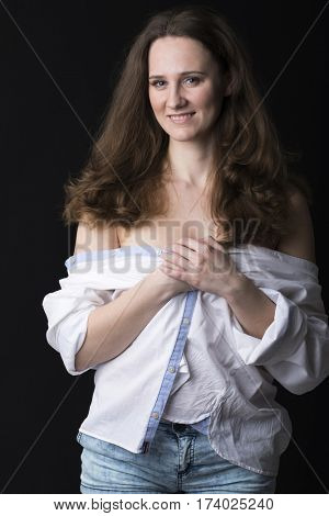 Closeup portrait of young brunette woman in white shirt, dark studio wall background