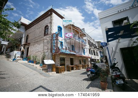 KALKAN, TURKEY - MAY 22 Narrow streets of Kalkan town in Mediterranean Turkey with stone houses cobblestone paved road restaurants and shops with blue sky and clouds 216