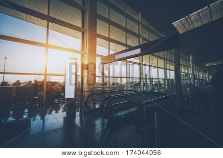 Moving staircase in hall of modern airport terminal with multiple passengers and taxis on street interior of airport with escalator going down huge window with cabstand people and bus stop outside