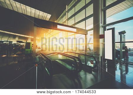 Moving staircase inside of modern airport terminal hall with multiple passengers waiting their flights interior of airport with escalator going down huge window with cabstand and cars outside